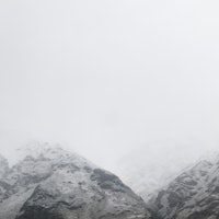 a mountain range covered in snow on a cloudy day